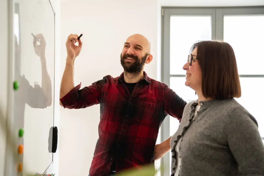 Un formateur explique un cas d'usage de l'IA au tableau blanc à une participante